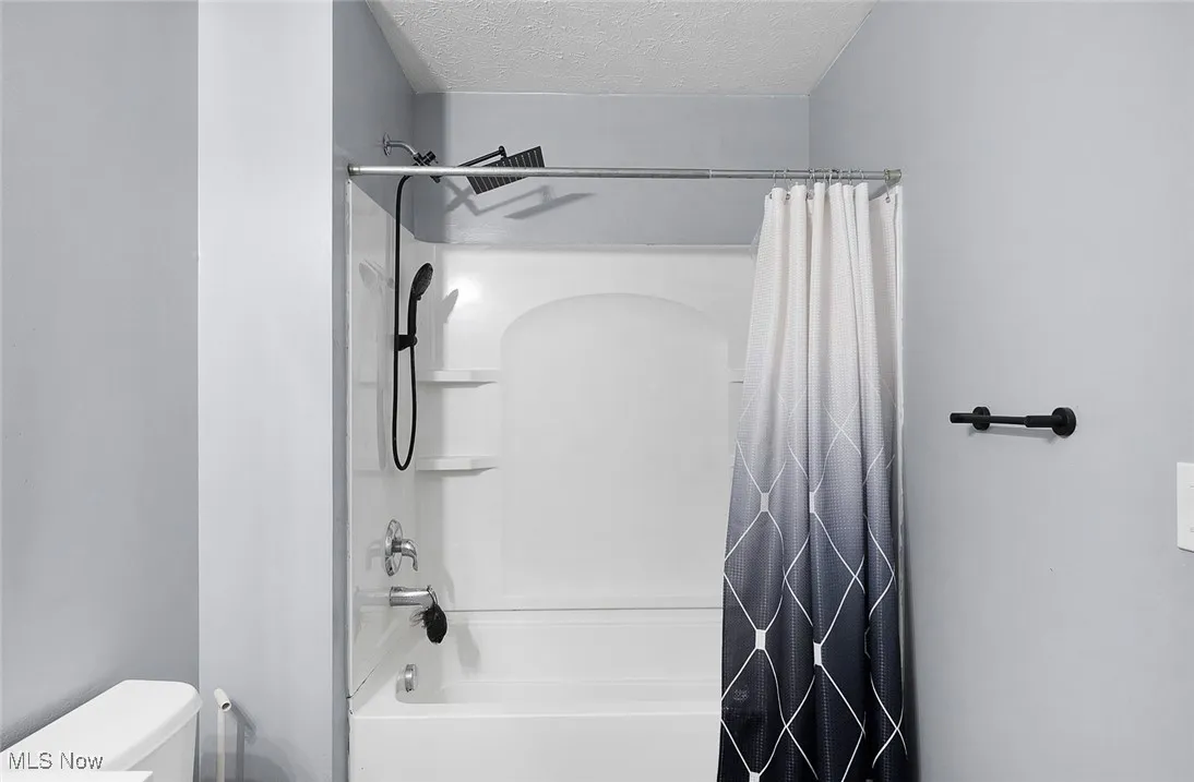Bathroom featuring shower / bathtub combination and a textured ceiling