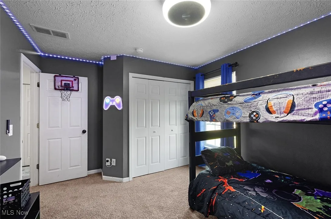 Bedroom with carpet floors, a textured ceiling, and a closet