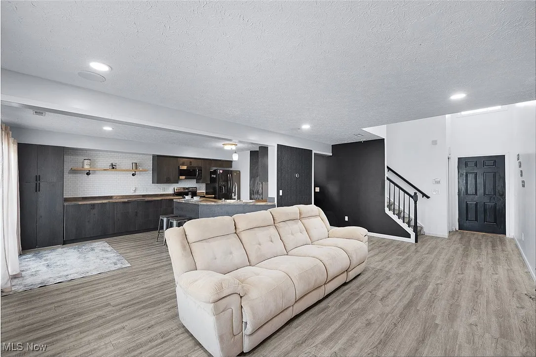 Living room with light wood-style floors, stairs, a textured ceiling, and recessed lighting