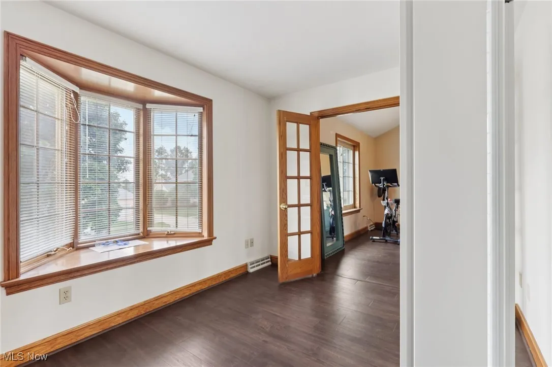 Unfurnished room with french doors, healthy amount of natural light, and dark wood finished floors