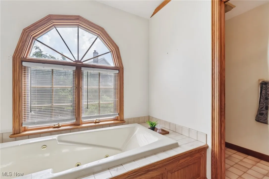 Full bathroom featuring healthy amount of natural light, a jetted tub, and tile patterned floors
