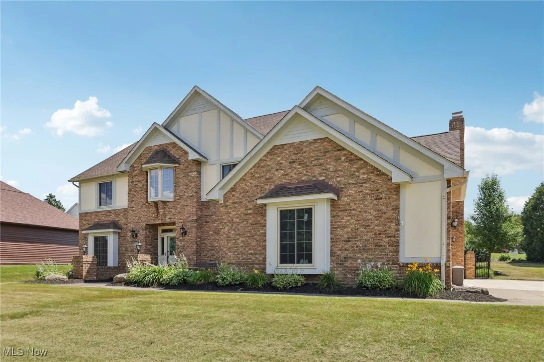 View of front of house featuring a chimney, a front lawn, brick siding, and board and batten siding