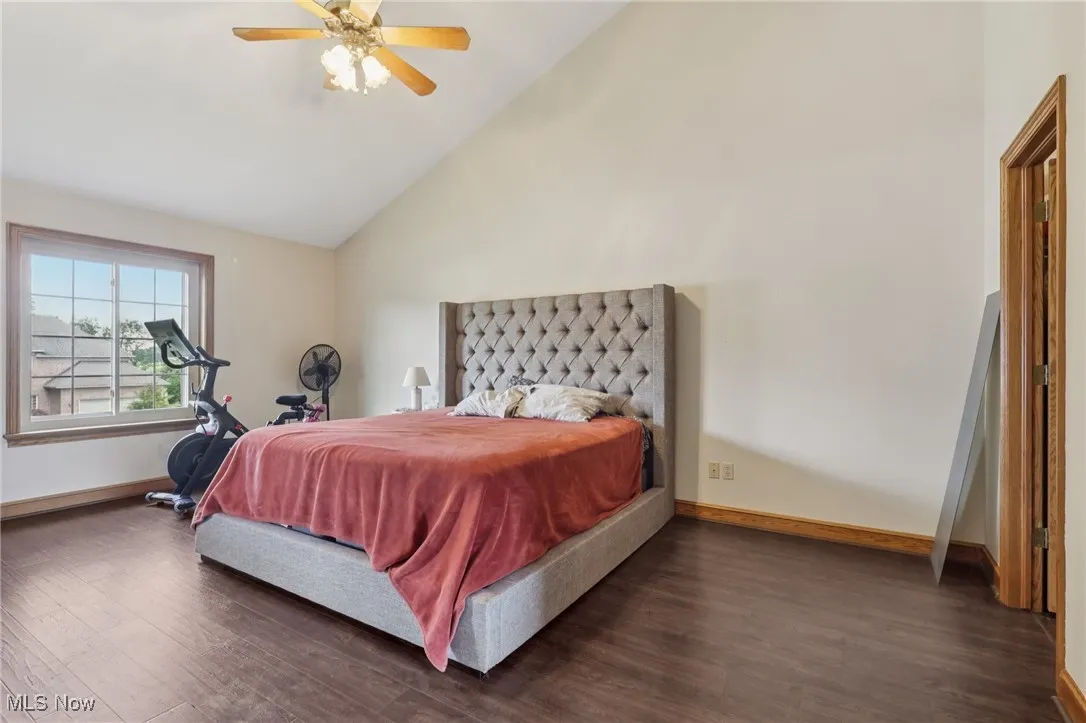 Bedroom featuring dark wood-type flooring, high vaulted ceiling, and a ceiling fan