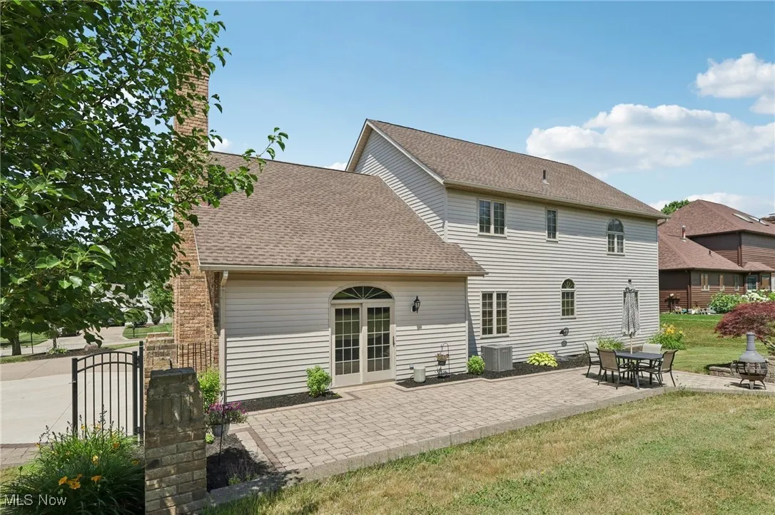 Back of property with a lawn, a patio area, and a shingled roof
