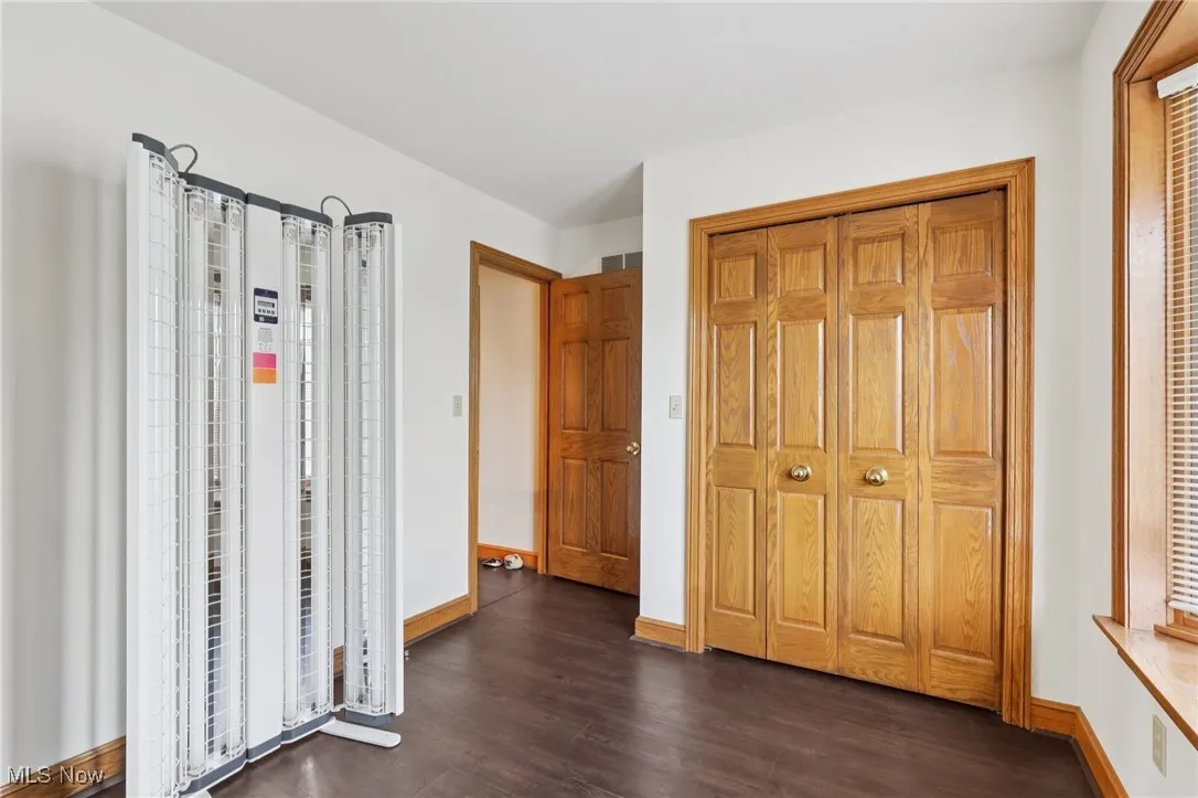 Unfurnished bedroom featuring dark wood finished floors and baseboards