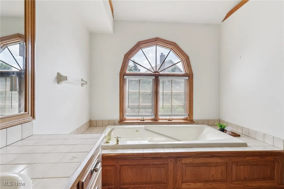 Full bath with plenty of natural light, a tub with jets, and vanity