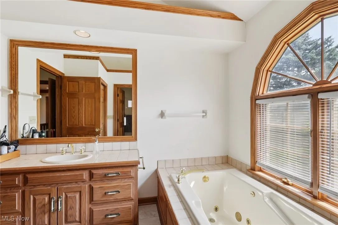 Full bath with a tub with jets, vanity, and tile patterned floors