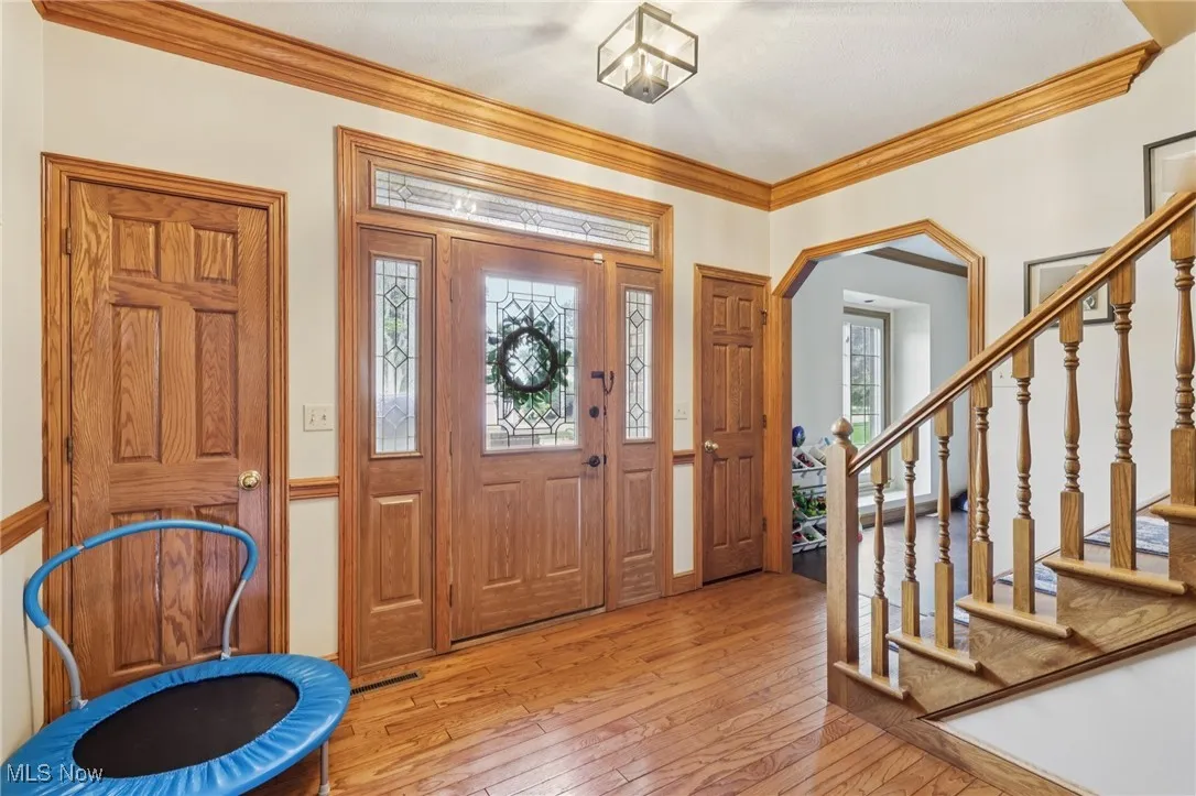 Foyer featuring wood-type flooring, ornamental molding, stairway, and arched walkways