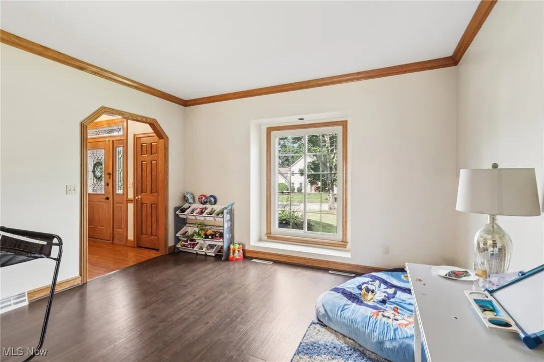 Bedroom featuring ornamental molding, wood finished floors, and arched walkways