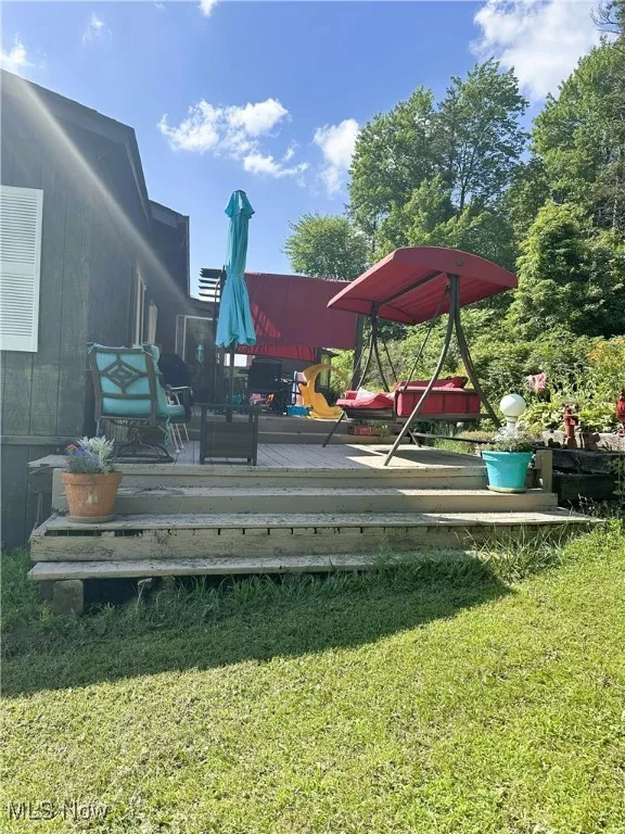 View of grassy yard featuring a deck