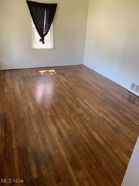 Unfurnished room featuring dark wood-style floors and baseboards