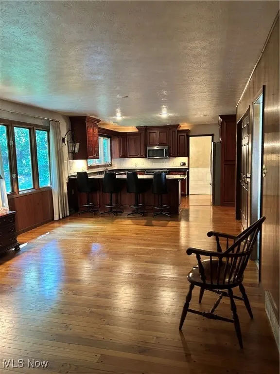 Kitchen with hardwood / wood-style flooring, a peninsula, fridge, a textured ceiling, and a breakfast bar