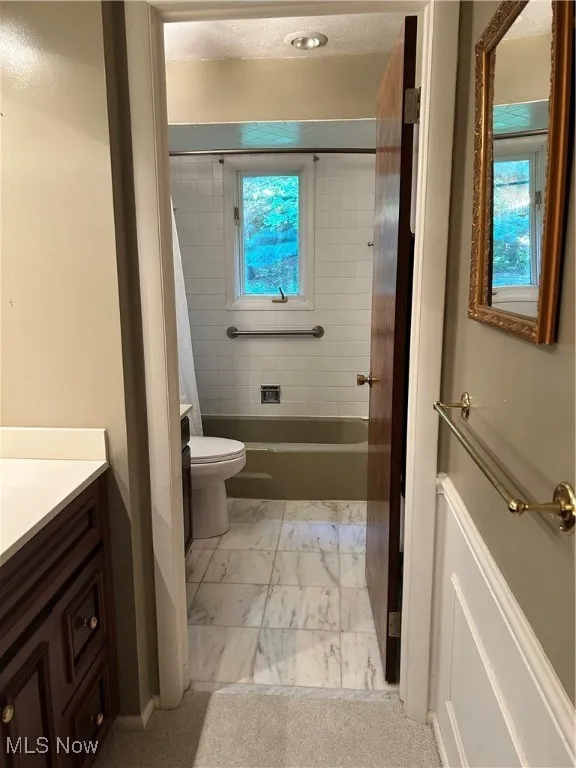 Full bathroom featuring vanity, healthy amount of natural light, marble finish flooring, and  shower combination