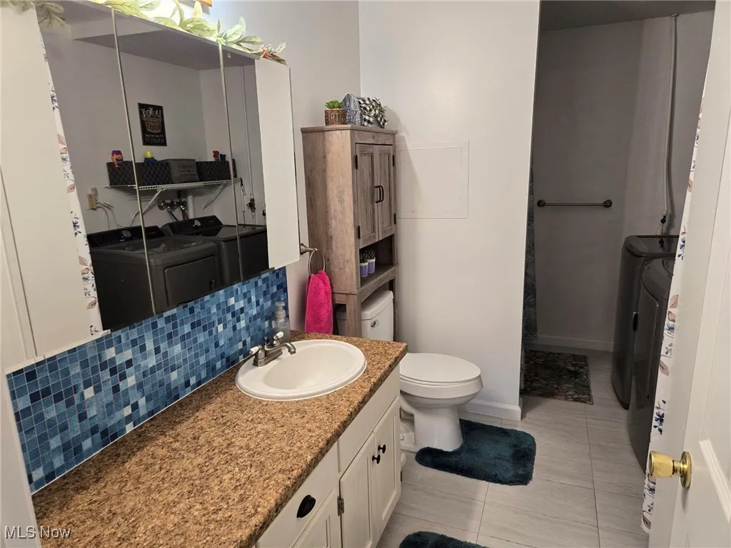 Bathroom with separate washer and dryer, vanity, and tile patterned floors
