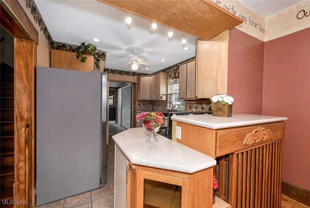 Kitchen with freestanding refrigerator, ceiling fan, light countertops, and recessed lighting