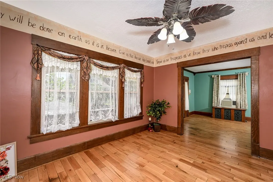 Unfurnished room with wood-type flooring, ceiling fan, and a textured ceiling