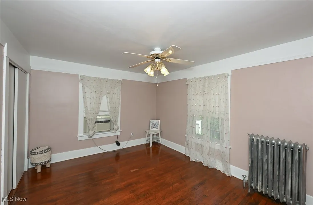 Spare room featuring radiator, wood finished floors, ceiling fan, and cooling unit