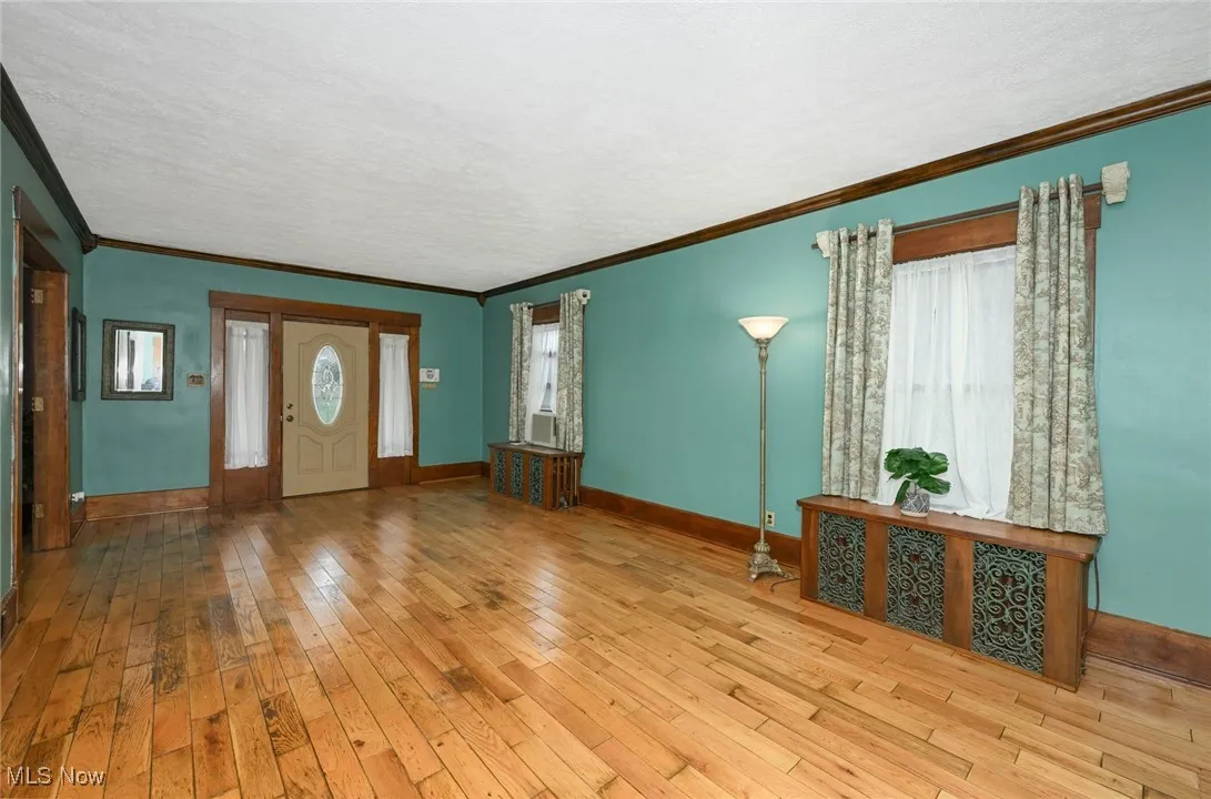 Foyer featuring wood-type flooring and ornamental molding