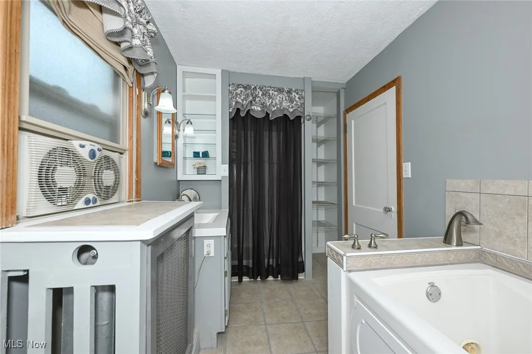 Full bath with a bath, tile patterned floors, and a textured ceiling