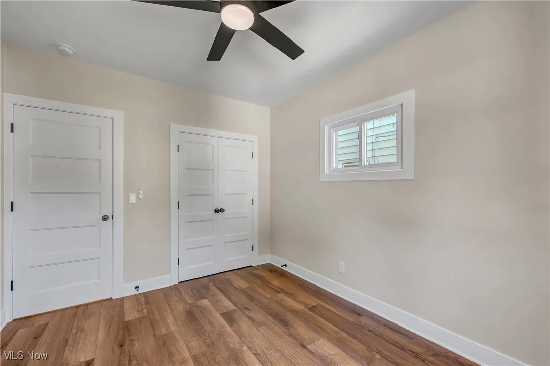 Unfurnished bedroom with wood finished floors, a closet, and a ceiling fan