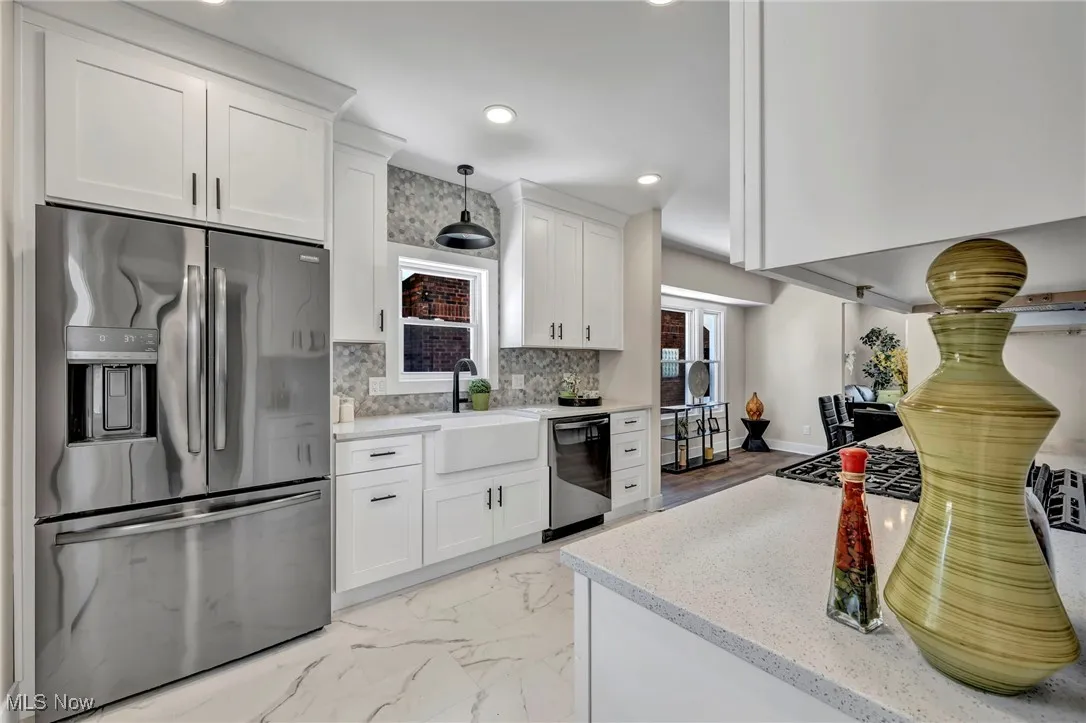 Kitchen featuring appliances with stainless steel finishes, white cabinets, light marble finish floors, backsplash, and recessed lighting