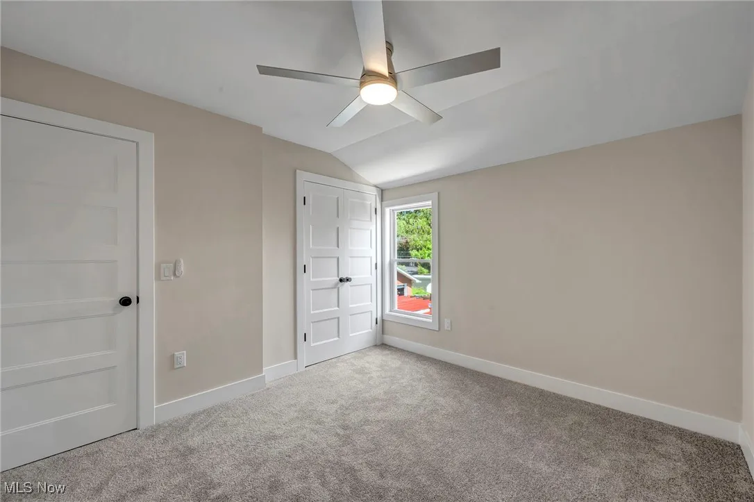 Unfurnished bedroom featuring lofted ceiling, carpet floors, and a ceiling fan