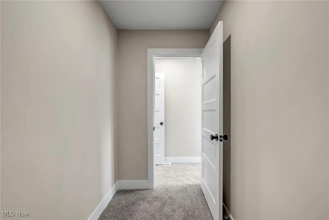 Hallway with carpet flooring and baseboards