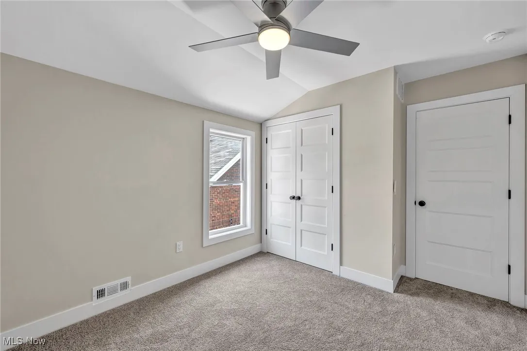 Unfurnished bedroom featuring carpet, vaulted ceiling, a ceiling fan, and a closet