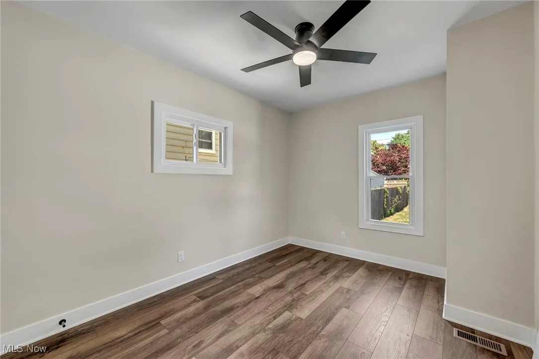 Unfurnished room with a ceiling fan and dark wood finished floors