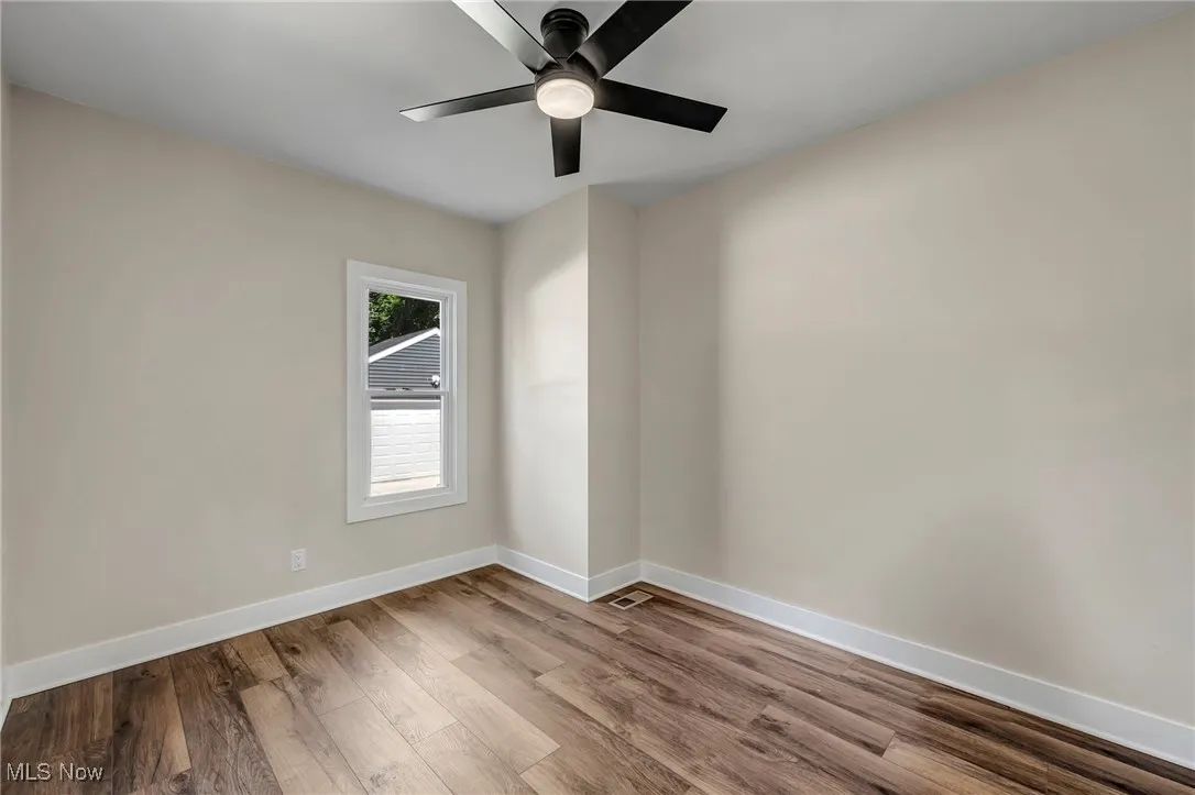 Empty room with wood finished floors and a ceiling fan