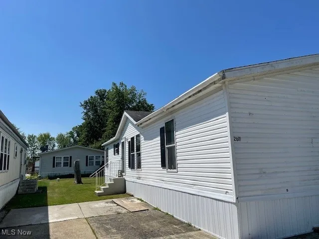 View of side of property featuring a lawn and a patio area