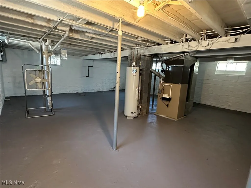 Below grade area with water heater, heating unit, and healthy amount of natural light