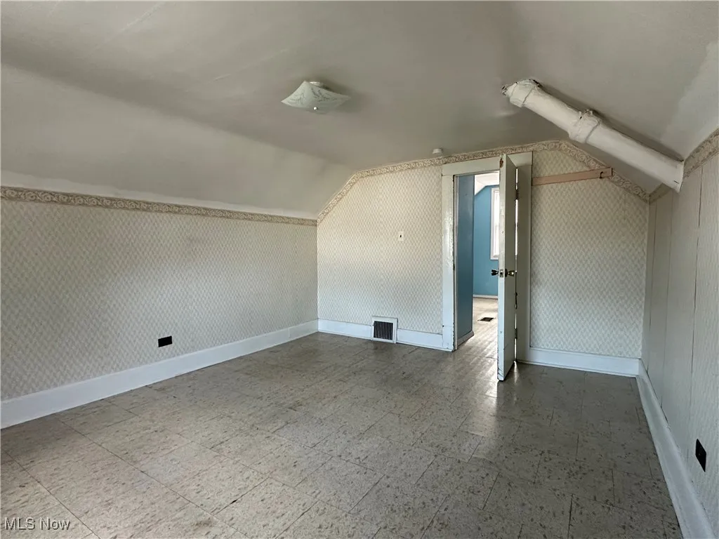 Additional living space featuring tile patterned floors and vaulted ceiling