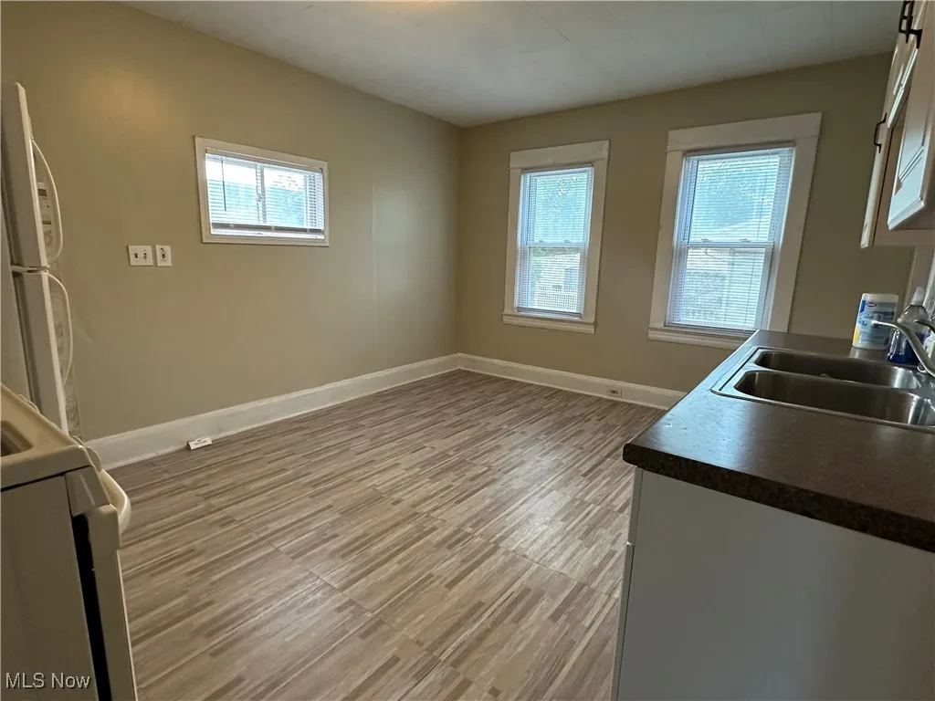 Kitchen with freestanding refrigerator, dark countertops, range, and light wood-type flooring