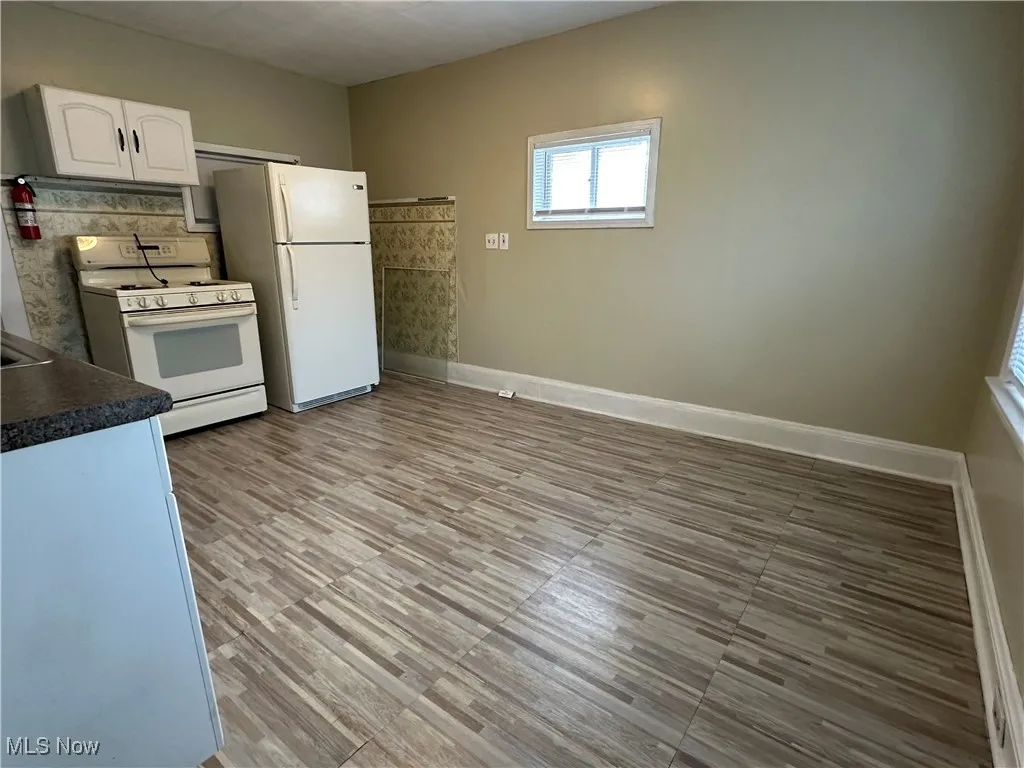 Kitchen with white appliances, dark countertops, and white cabinetry