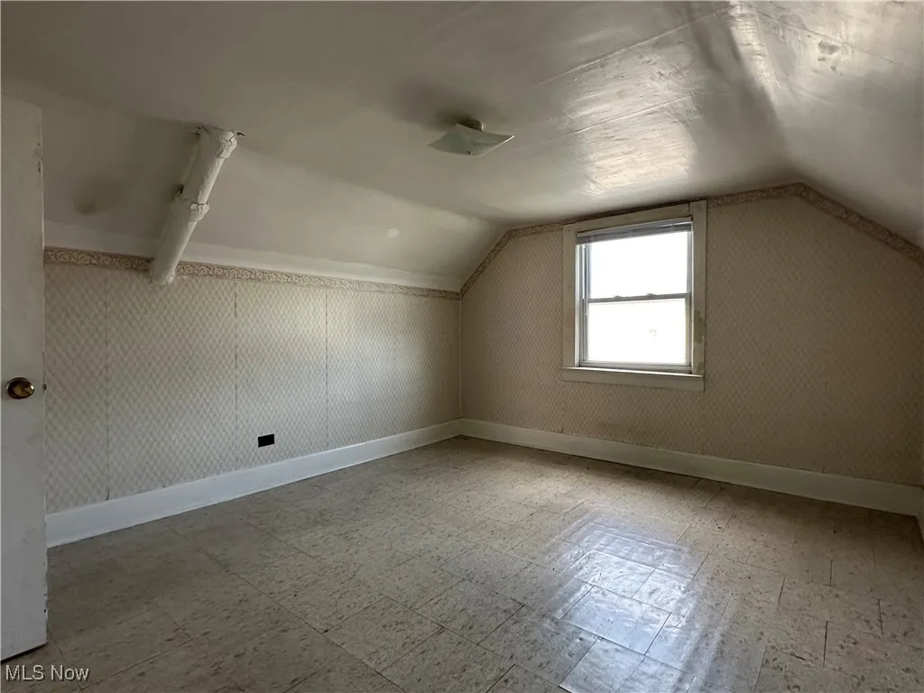 Additional living space with tile patterned floors and vaulted ceiling