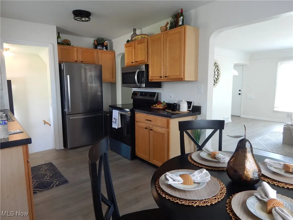 Kitchen with appliances with stainless steel finishes, light wood-style flooring, and arched walkways