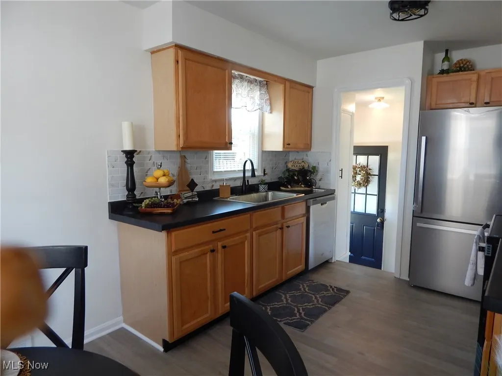 Kitchen with stainless steel appliances, LVT finished floors, decorative backsplash.