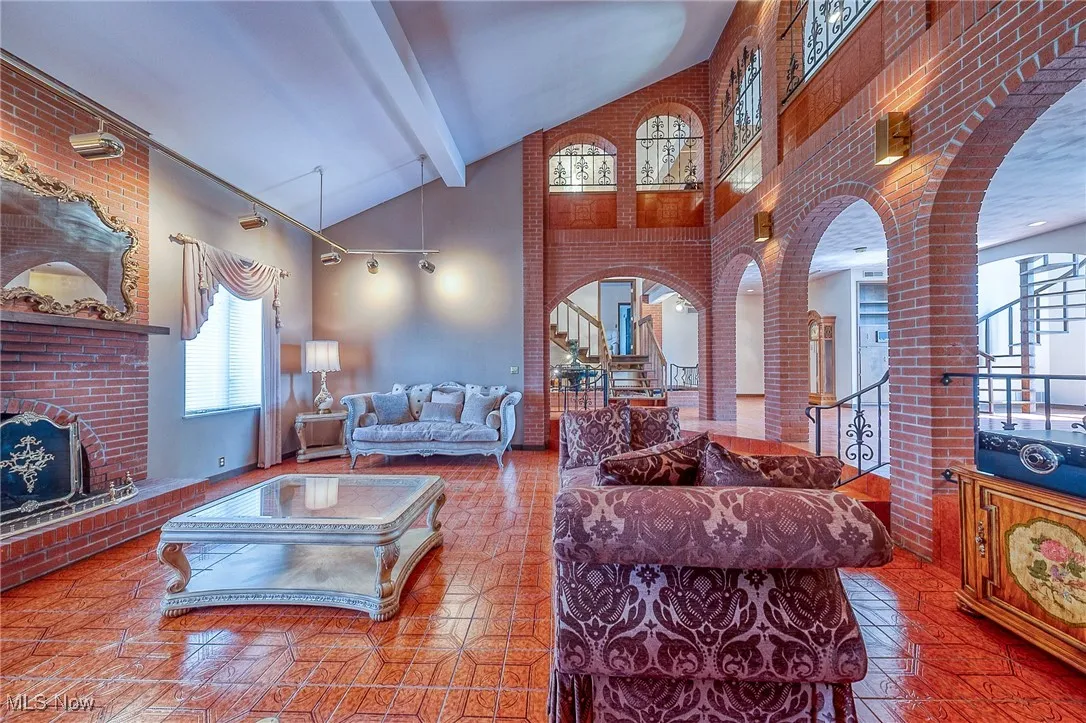 Living room with high vaulted ceiling, arched walkways, a fireplace, beamed ceiling