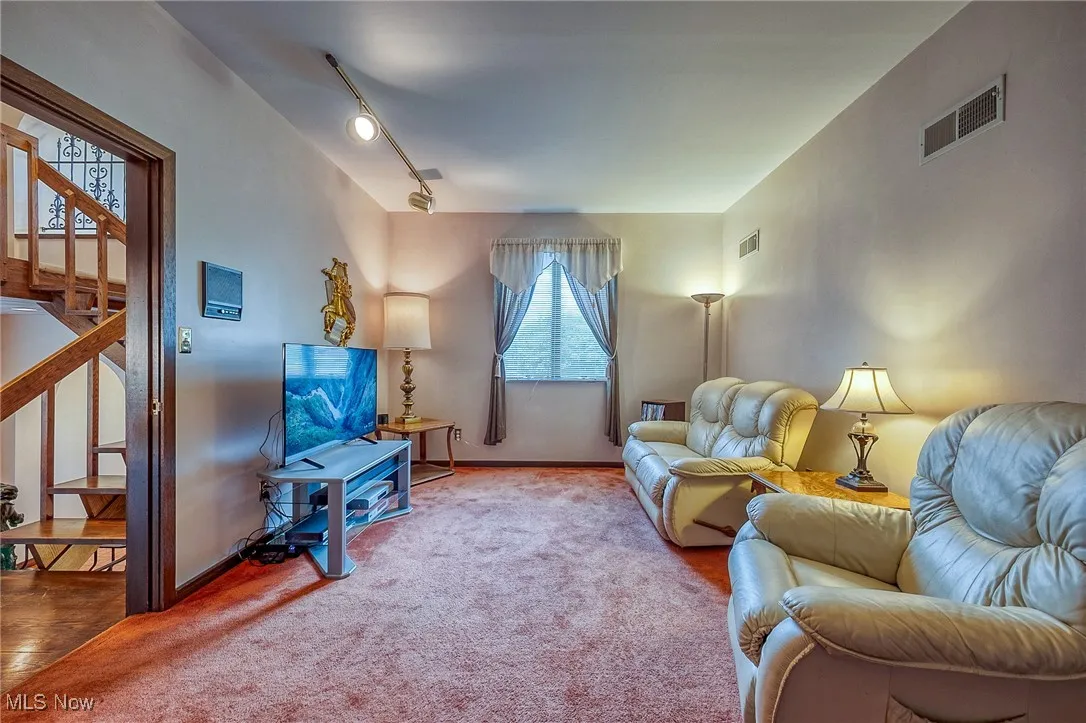 Living area featuring stairway, carpet floors, and track lighting