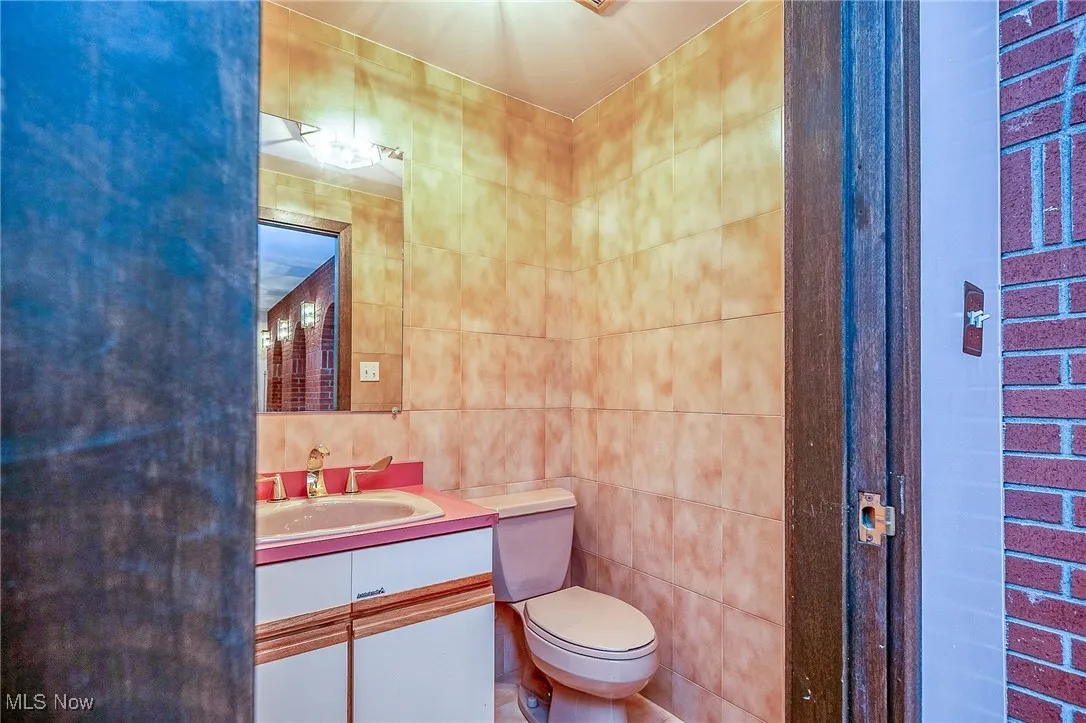 Half bath with tile walls and vanity