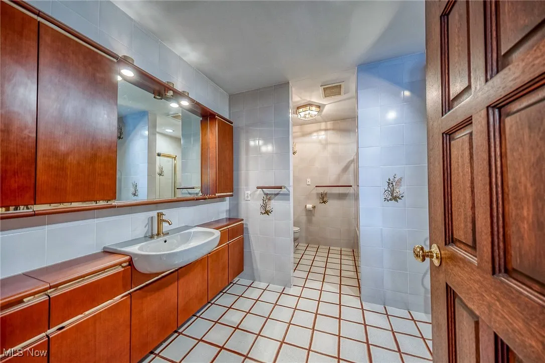 Full bathroom featuring tile patterned flooring, vanity, tile walls, and decorative backsplash