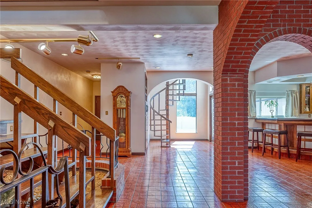 Entrance foyer featuring arched walkways, healthy amount of natural light, stairs, and ornate columns