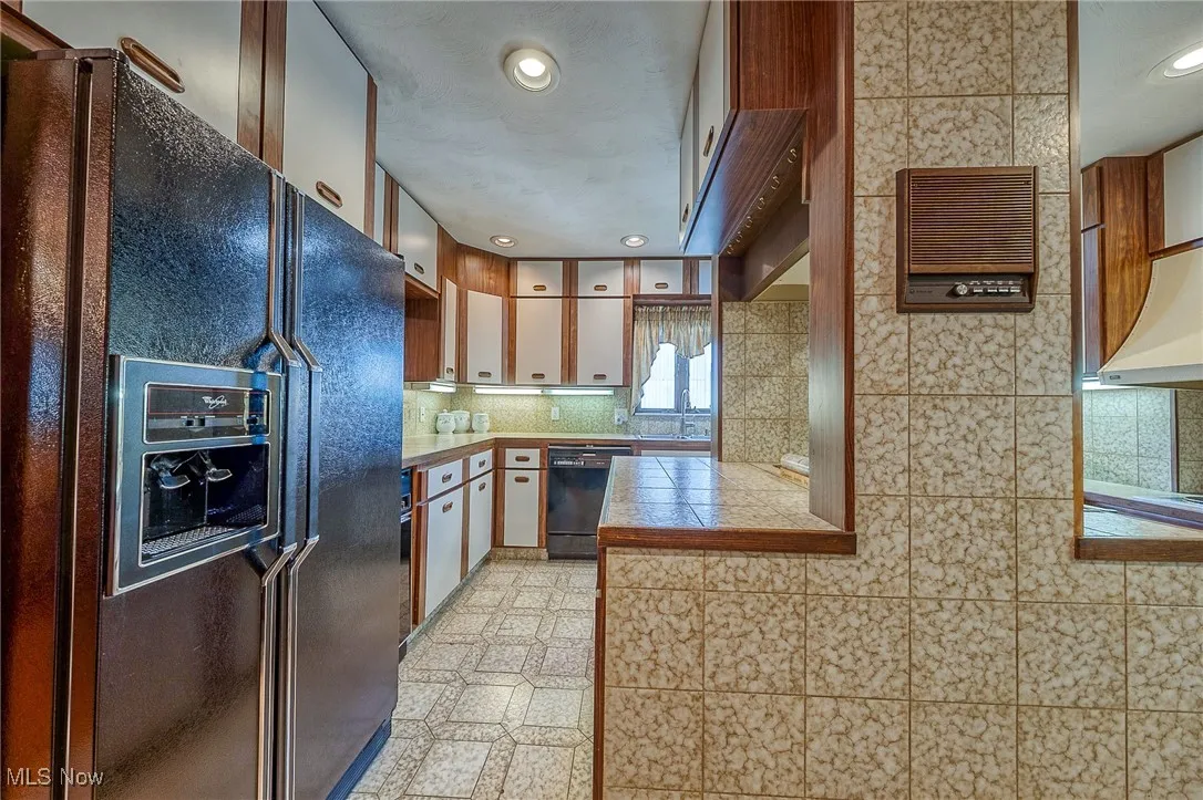 Kitchen featuring black appliances, recessed lighting, tasteful backsplash, light floors, and tile countertops