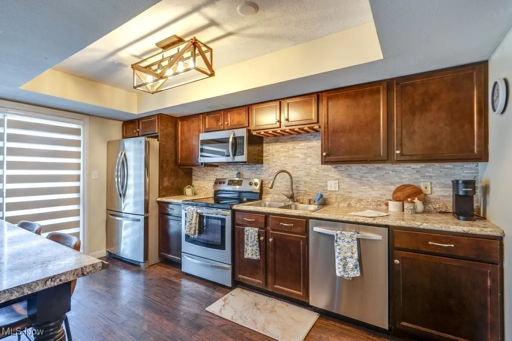Kitchen featuring stainless steel appliances, dark wood-type flooring, light countertops, and decorative backsplash