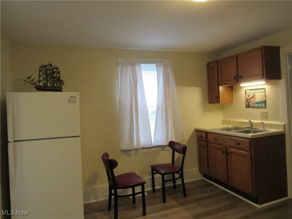Kitchen refrigerator with double stainless steel sinks, cabinetry, window treatment & newer LTV flooring!
