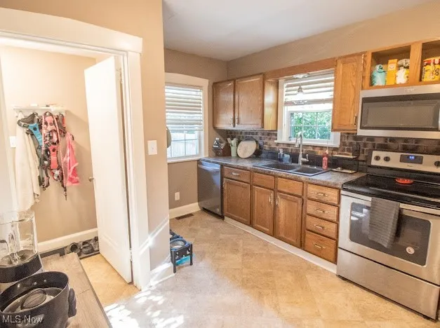 Kitchen with appliances with stainless steel finishes, dark countertops, backsplash, and brown cabinets