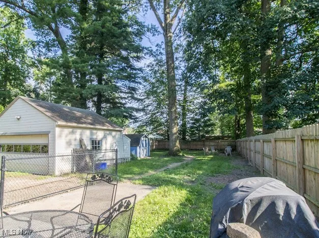 Fenced backyard featuring a garage and a storage unit