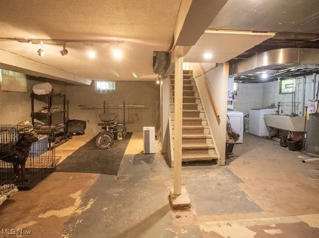 Below grade area featuring independent washer and dryer, stairs, and water heater