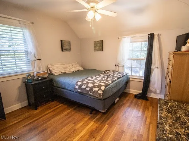 Bedroom with wood finished floors, vaulted ceiling, and a ceiling fan